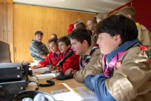 Scouts gathered around a desk microphone at a Jamboree on the Air amateur radio station