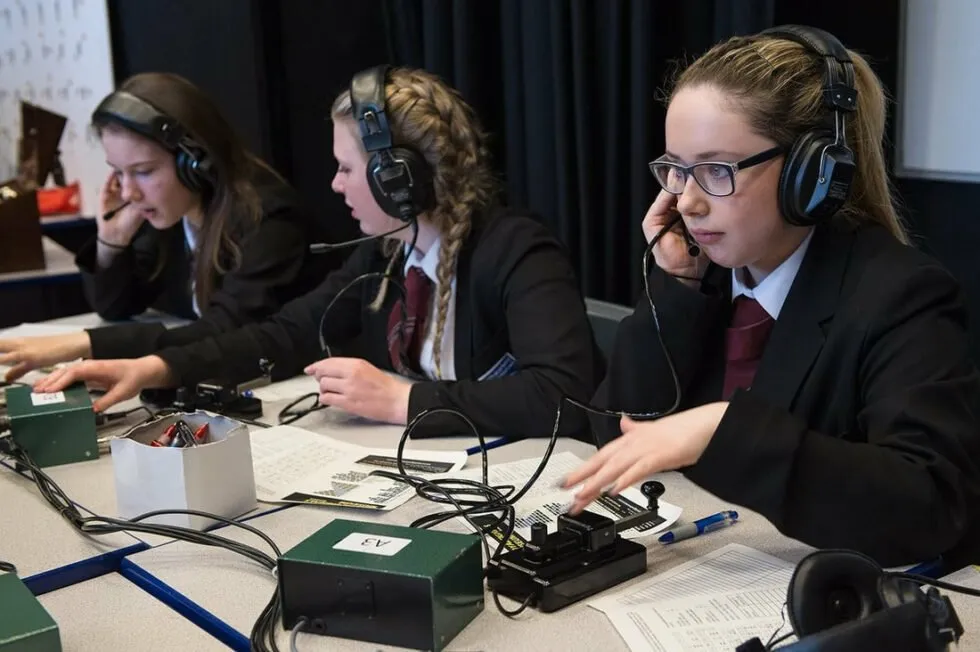 Three school students operating an amateur radio station during an ARISS contact with the International Space Station.