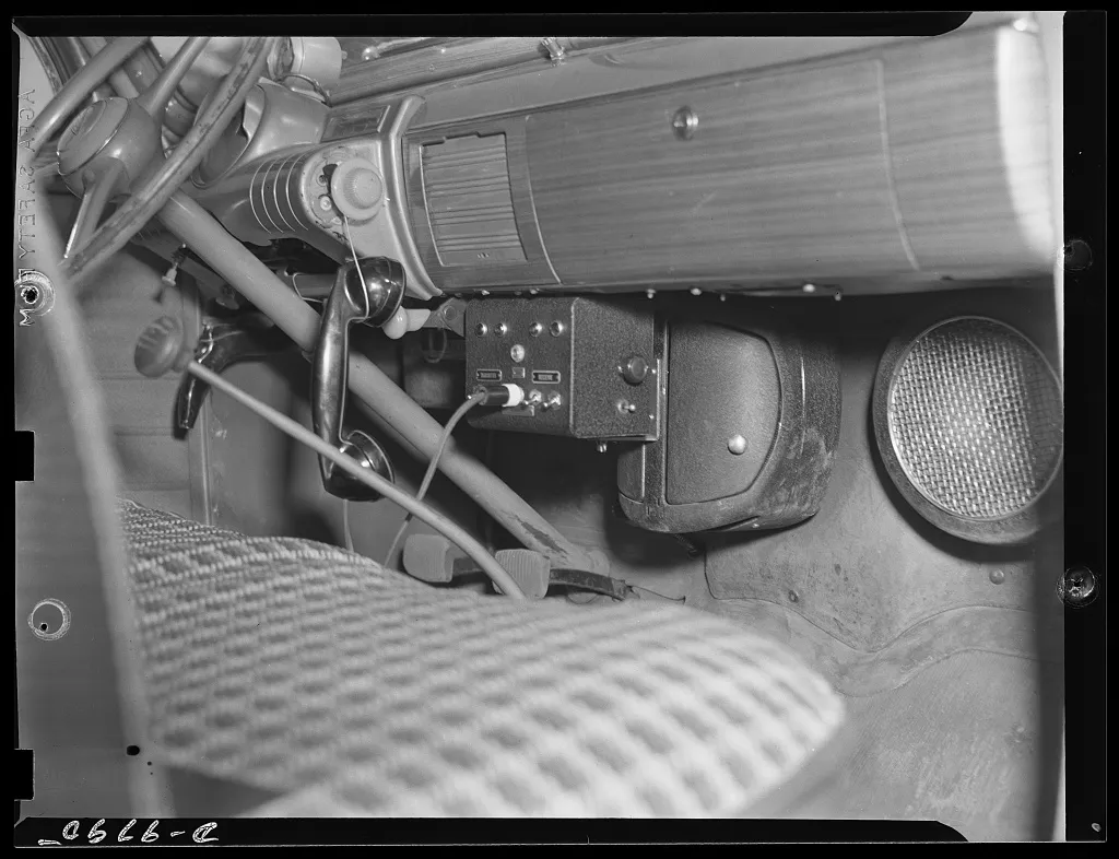 A wartime War Emergency Radio Service mobile two-way radio set installed under the dashboard of a car, with its handset and speaker, built and operated by amateur radio operators for civil defense.